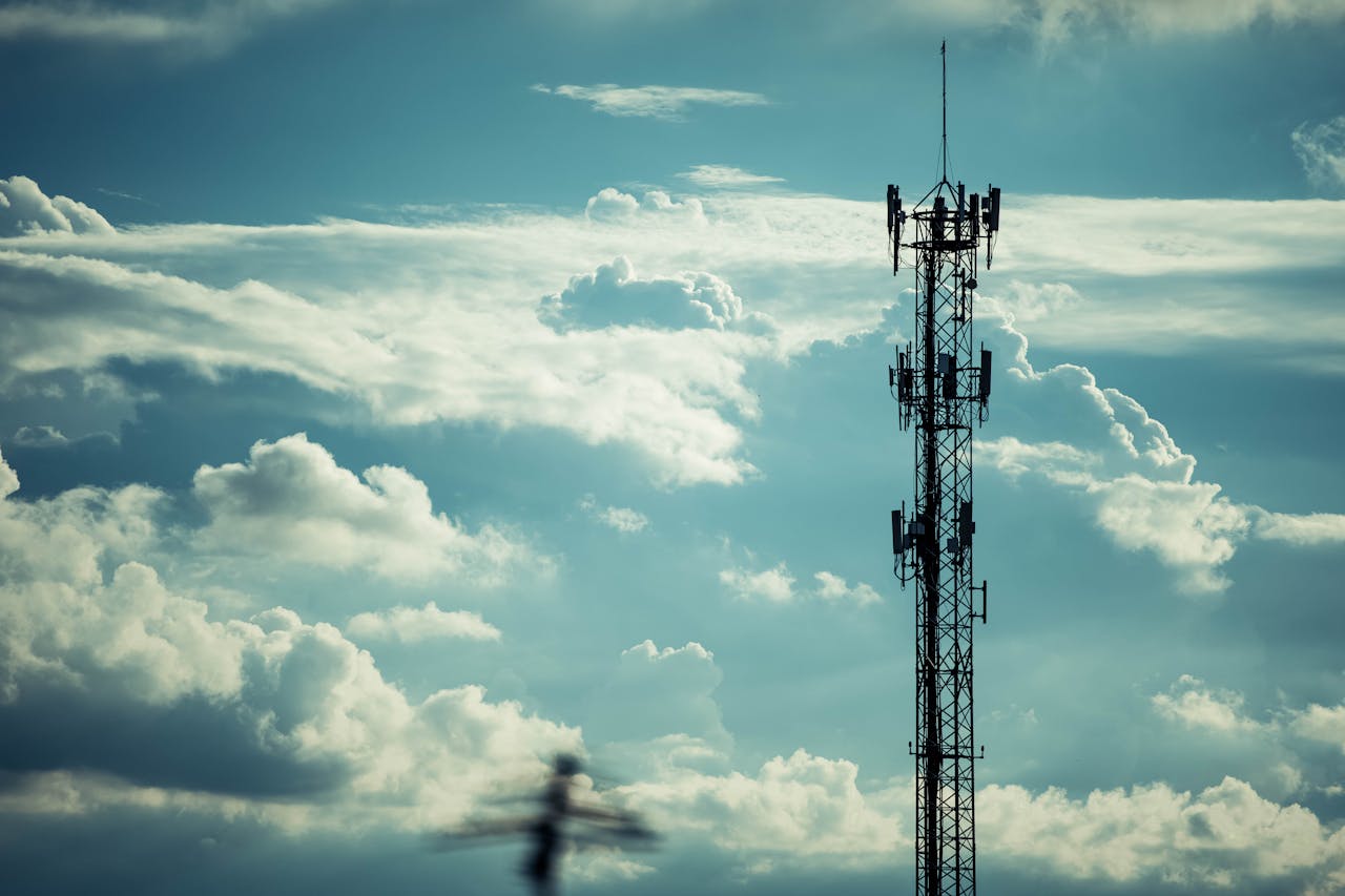 A tall communication tower silhouetted against a bright, cloudy sky, symbolizing connection.