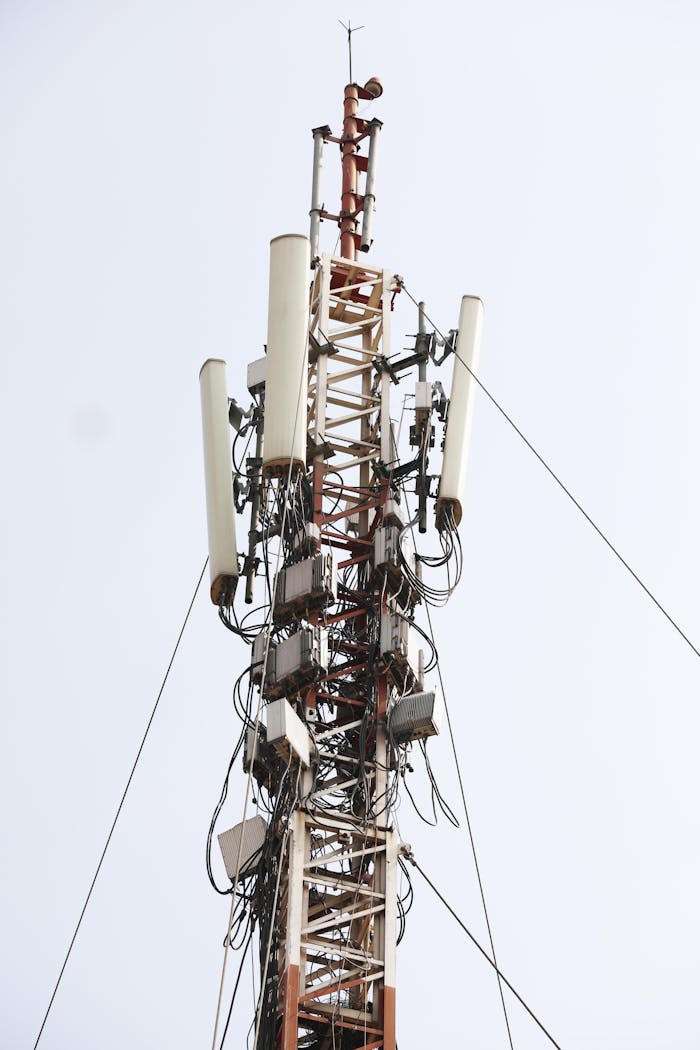 Close-up of a tall communication tower with antennas against a clear sky.